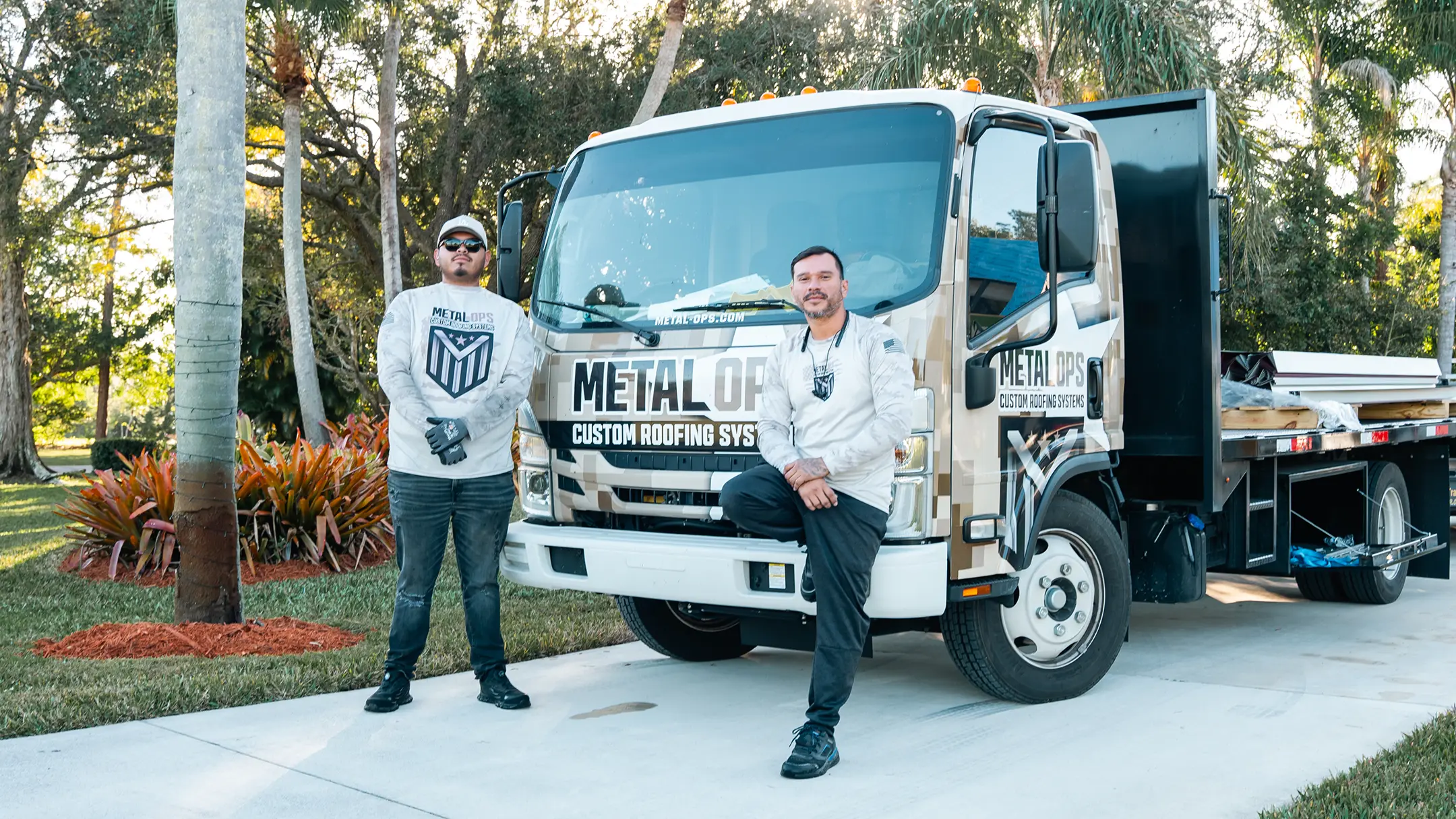 Two men in work uniforms stand by a truck labeled 